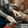 Junge Frau in Arbeitsbekleidung die einen Kurbelwelle zerlegt vor sich hat um diese zu reparieren