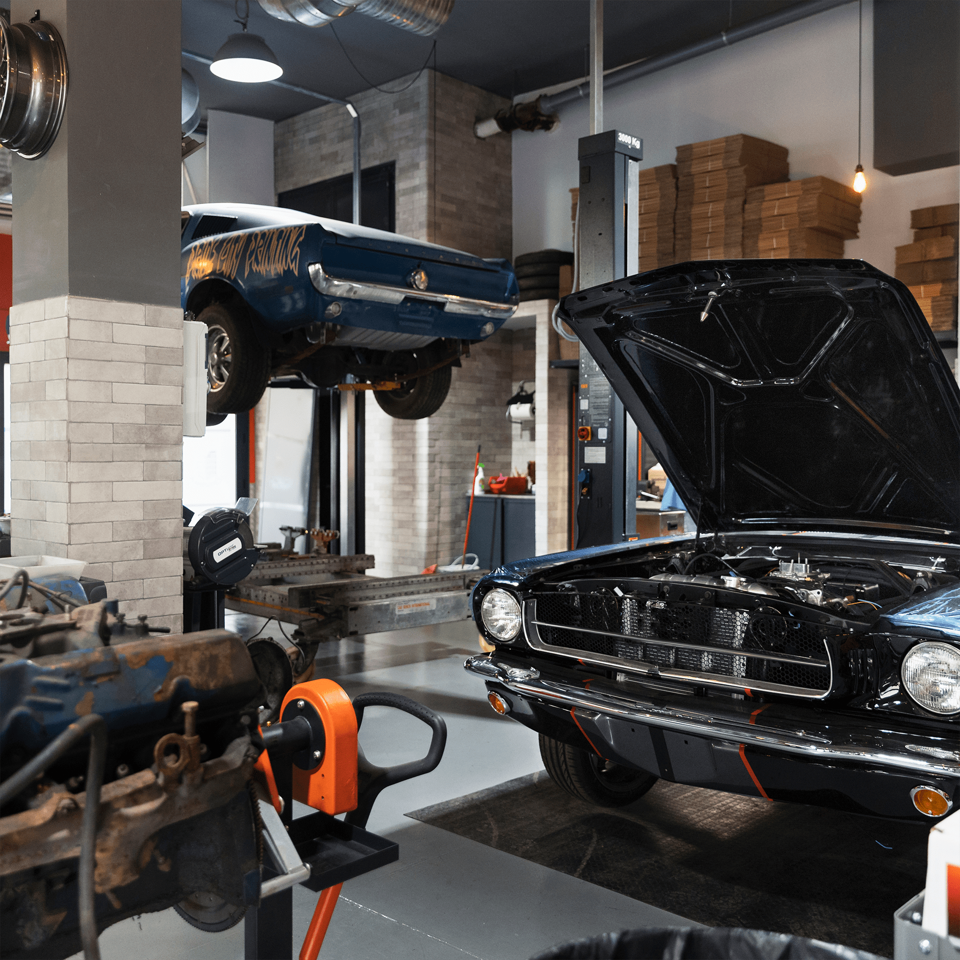 Werkstatt mit Hebebühne auf der gerade zwei Ford Mustangs repariert werden
